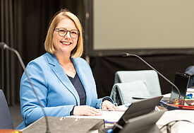 Demokratie braucht Beteiligung – und Menschen mit Haltung Präses Anja Fährmann sitzt am Laptop und lächelt in. die Kamera.