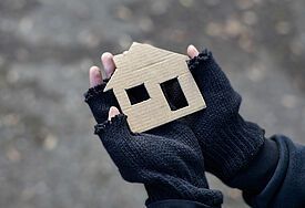 Keine Wärme, kein Schutz: In der Weihnachtszeit sind Armut und Obdachlosigkeit besonders hart Obdachloser Junge hält ein Karton-Haus in den Händen