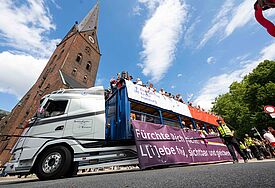 300.000 Menschen feiern CSD in Hamburg Ein großer CSD-Truck mit Bannern fährt an einem Kirchturm in Hamburg vorbei