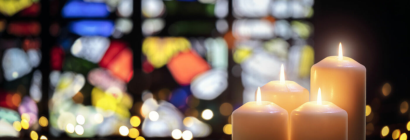 Adventslichter vor einem Kirchenfenster