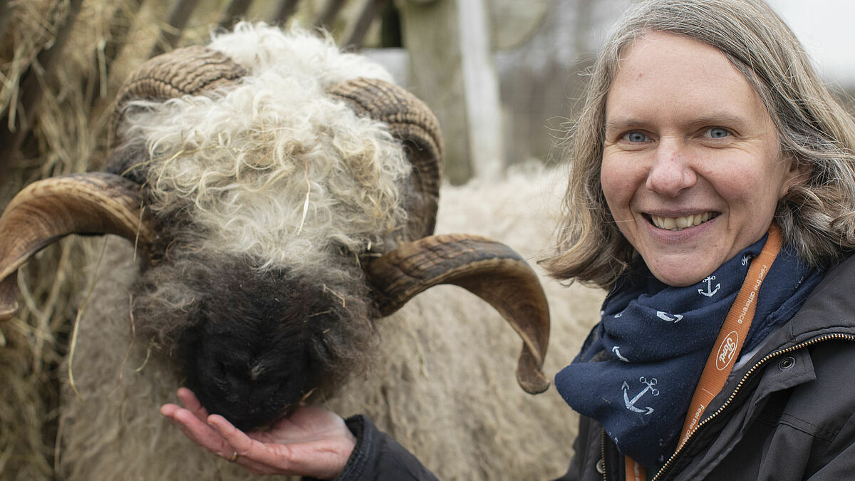 Tierparkpädagogin Stefanie Klingel mit einem Walliser Schwarznasenschaf im Streichelgehege der Arche Warder.