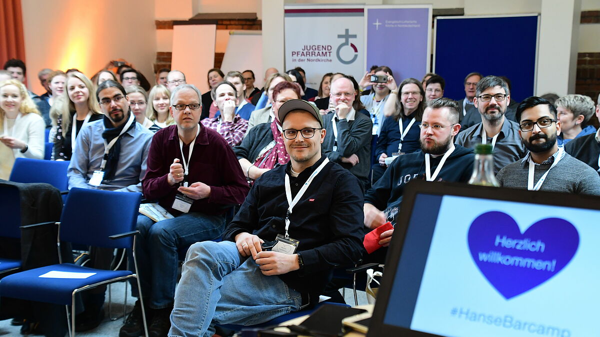 Kurz vor der Keynote von Martin Fehrensen (Mitte, erste Reihe) werden die Teilnehmerinnen und Teilnehmer des Hansebarcamps begrüßt.