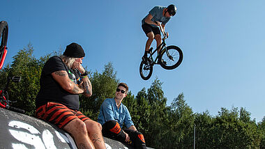 Mit einem Besuch im Skate- und BMX-Park "Sportpiraten" hat die Präses der Synode der Evangelischen Kirche in Deutschland (EKD), Anna-Nicole Heinrich (re.), am Montag ihre Erkundungstour durch Deutschland begonnen. Heinrich sprach mit dem Gründer des Vereins, Dirk Dillmann (li.), und Teamern.