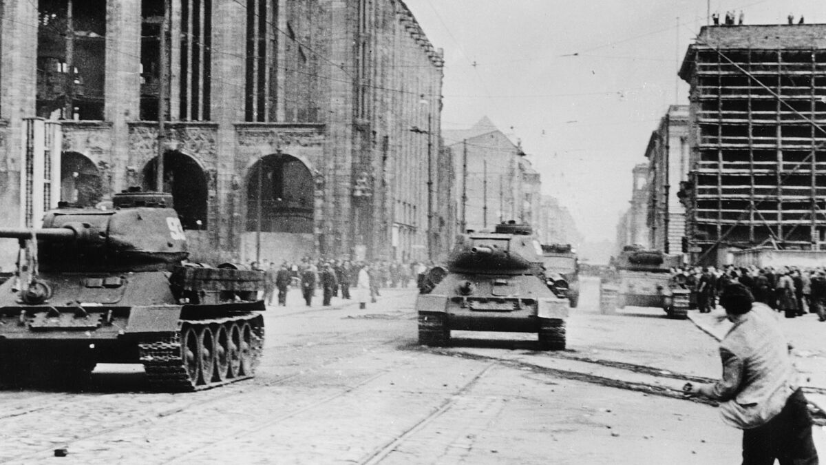 Menschen werfen Steine auf die Panzer, die den Aufstand niederschlagen sollen. 