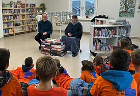 Bischof Tilman Jeremias liest den Kindern der xxx Schule vor. Neben ihm sitzt Gemeindepädagogin Kerstin Blümel