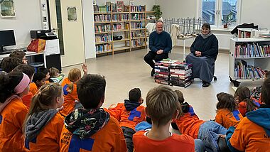 Bischof Tilman Jeremias liest den Kindern der xxx Schule vor. Neben ihm sitzt Gemeindepädagogin Kerstin Blümel