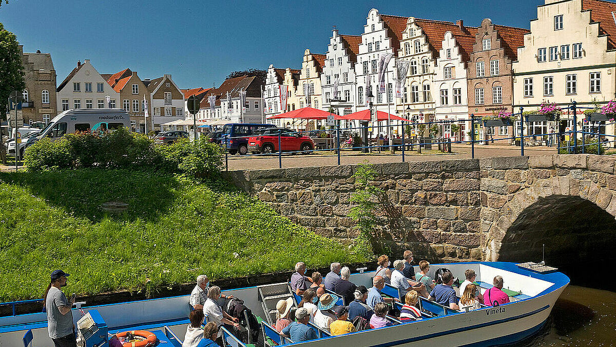 Bootsfahrt auf der zentralen Gracht am Mittelburggraben in Friedrichstadt, Schleswig-Holstein, mit Giebelhäusern am Markplatz. Mit ihren Kanälen, Brücken und Giebeln gleicht Friedrichstadt einer holländischen Idylle.