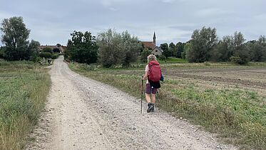 Sandweg mit Pilgerin und dem Kloster Tempzin im Hintergrund