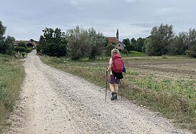 Sandweg mit Pilgerin und dem Kloster Tempzin im Hintergrund