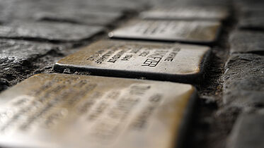 In eine Kopfsteinpflasterstraße eingelassen Stolpersteine. 