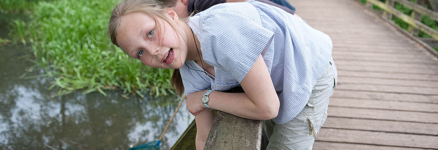 Ein Kind lehnt auf einer Brücke, die über einen Fluss führt