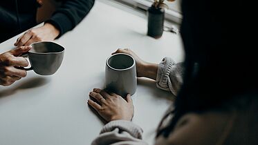 Gespräch Kaffeebecher und zwei Paar Hände