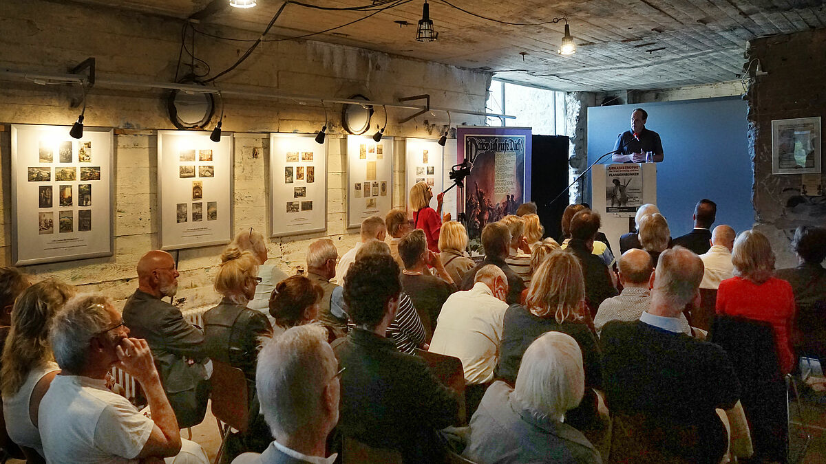 Pastor Michael Schwer spricht im Flandernbunker zur Eröffnung der Ausstellung "Gott mit uns - Kirchliche und religiöse Propaganda für Krieg und Vaterland".