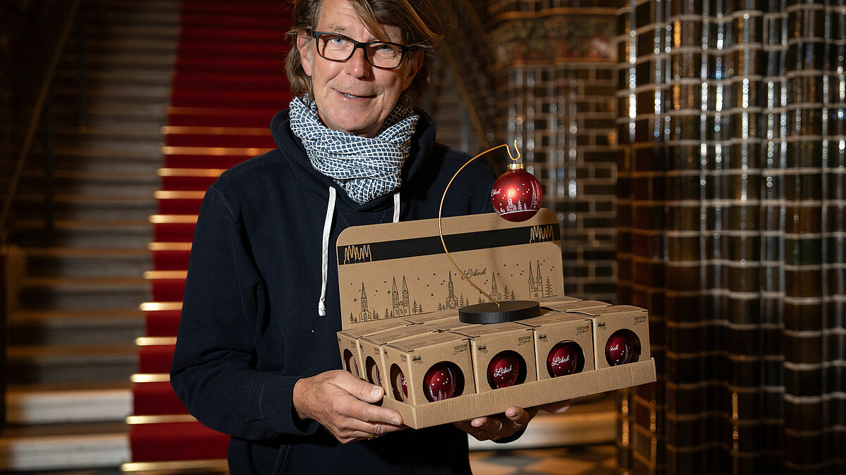 So sehen die ersten Lübecker Christbaumkugeln aus: Geschäftsmann Carsten Albrecht präsentiert die roten Schmuckstücke mit den sieben Altstadtkirchen. 