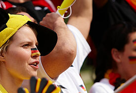 Fußballfans mit Hüten, Flaggen und Winkelementen fiebern mit