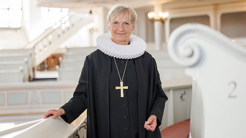 Bischöfin Kirsten Fehrs steht in Ornat und mit Bischofskreuz vor einer Sitzreihe in der Hamburger Hauptkirche St. Michaelis