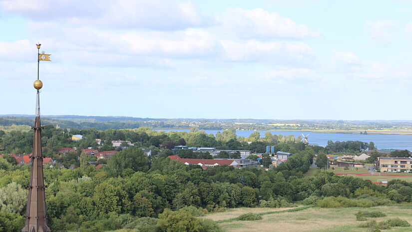 Der Blick auf Felder östlich der Stadt Schleswig mit der Förde Schlei im Hintergrund