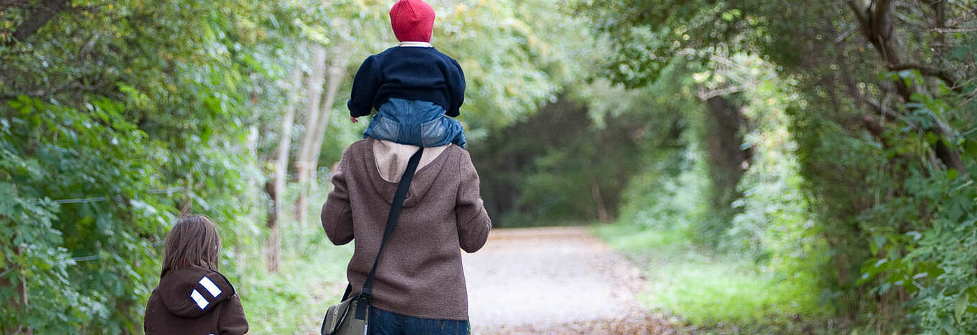 Ein Vater mit zwei Kindern spaziert im herbstlichen Wald