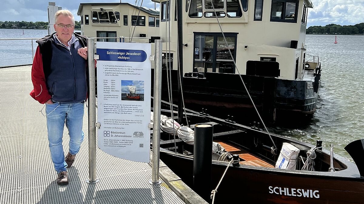 Pastor Michael Bruhn neben dem Jesusboot im Schleswiger Hafen.