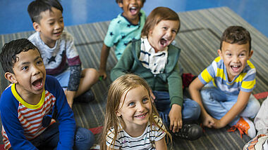 Kinder sitzen auf dem Boden und singen