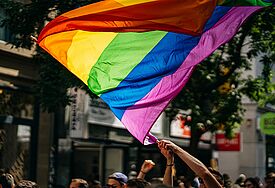 Hand, die eine Regenbogenflagge auf der Straße schwenkt