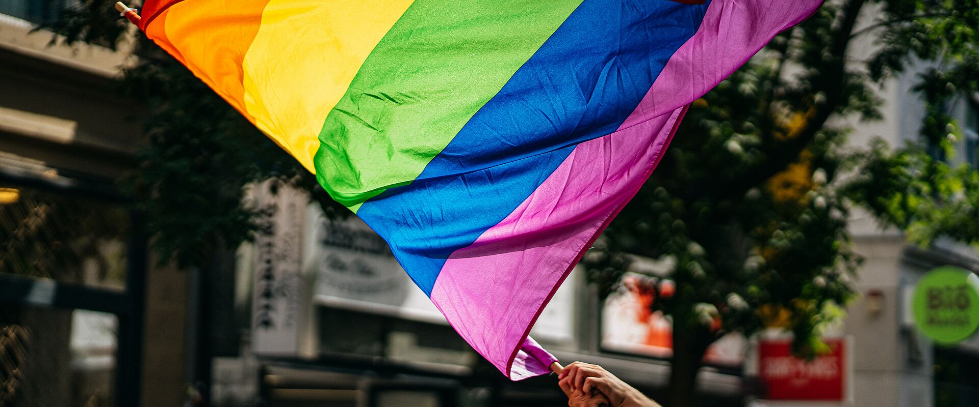 Hand, die eine Regenbogenflagge auf der Straße schwenkt