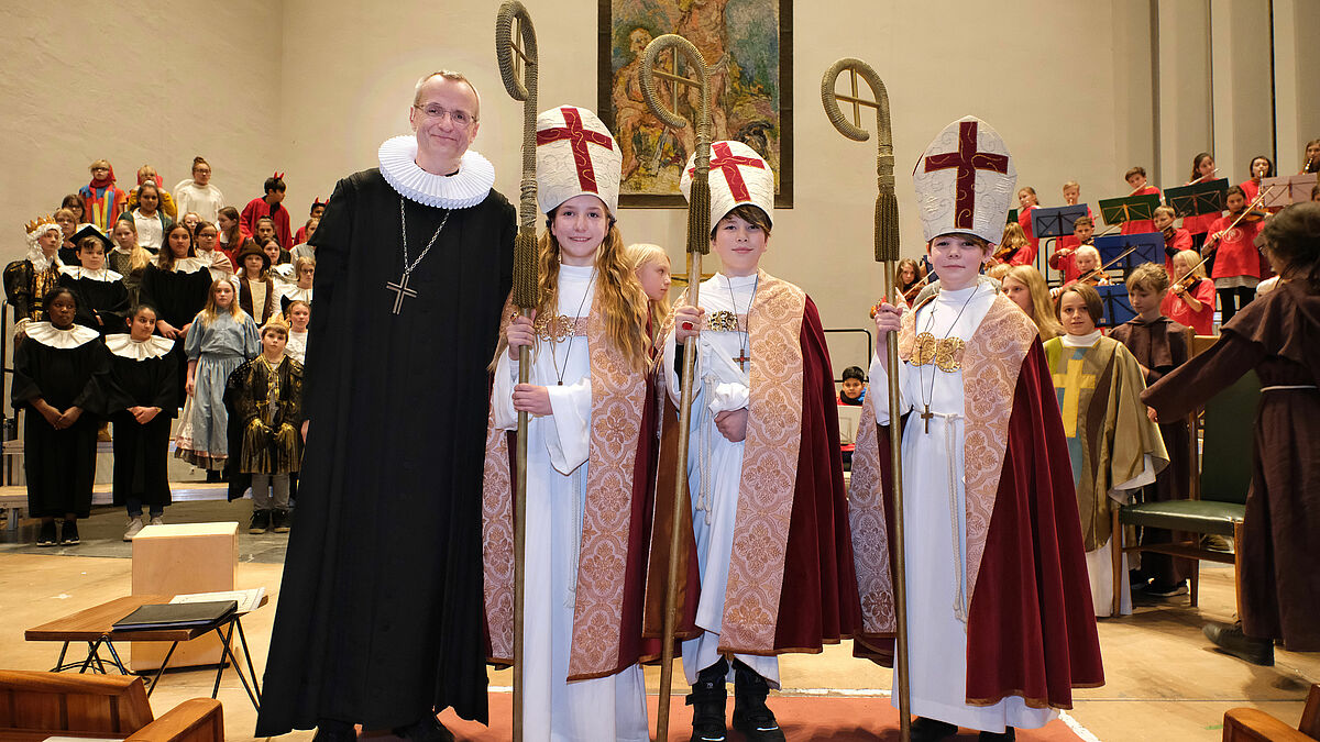 Die neuen Kinderbischöfe Rike Sonnenberg (10, r.), Kira Hoffmann (10, l.) und Connor Slupkowski (11, M.) mit Hauptpastor Martin Vetter in der Hamburger Hauptkirche St. Nikolai. 
