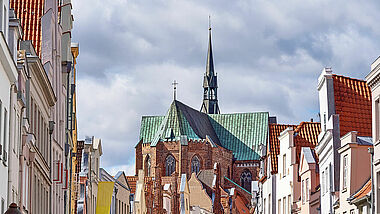 Die Glockengießerstraße ist mit bunten Wimpeln geschmückt. Die Katharinenkirche am Ende der Straße hat ein grünes Kupferdach.