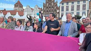 Auf dem Marktplatz breiten Bürger:innen und Kirchentagsteilnehmer:innen ein riesiges Friedenszeichen aus. 