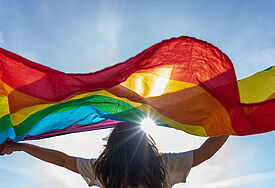 Frau mit Regenbogenflagge im Sonnenschein