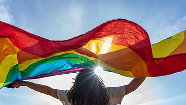 Frau mit Regenbogenflagge im Sonnenschein