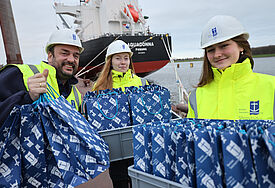 Helfer:innen bringen in gelben Warnwesten Geschenke zu einem Containerschiff 