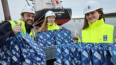 Helfer:innen bringen in gelben Warnwesten Geschenke zu einem Containerschiff 