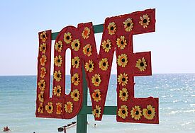 Love-Schild mit Blumen am Strand