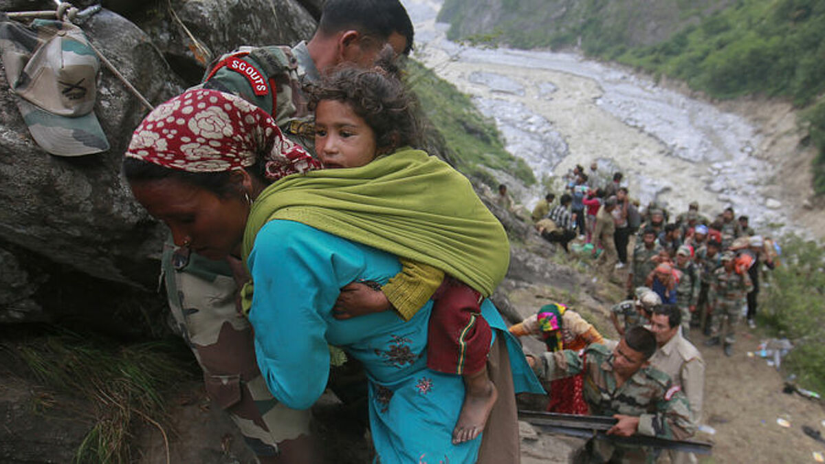 Soldaten helfen einer Frau mit Kind auf dem Rücken während der Rettungsaktion in Godvindghat im Himalaya.