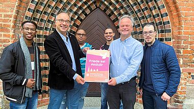 Bischof Jeremias (2.von rechts) lädt gemeinsam mit dem pommerschen Ökumenebeauftragten Gerrit Marx (2. von lenks) zum Friedenszeichen beim Kirchentag in Greifswald ein.