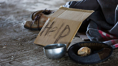 Pappschild mit der Aufschrift "Help" vor Decken und einem Topf