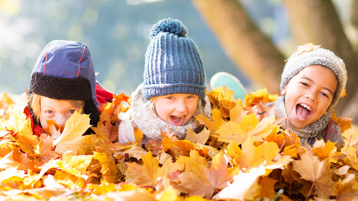 Kinder spielen im Herbstlaub