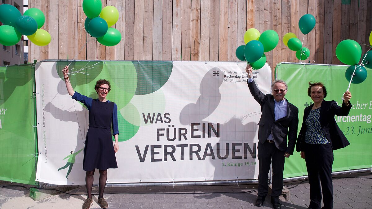 "Was für ein Vertrauen": Julia Helmke (Generalsekretärin des Kirchentags, v.l.), Hans Leyendecker (Präsident des 37. DEKT) und Annette Kurschus (Präses der Evangelischen Kirchen von Westfalen) präsentieren das Kampagnenmotiv für den 37. Deutschen Evangelischen Kirchentag in Dortmund.