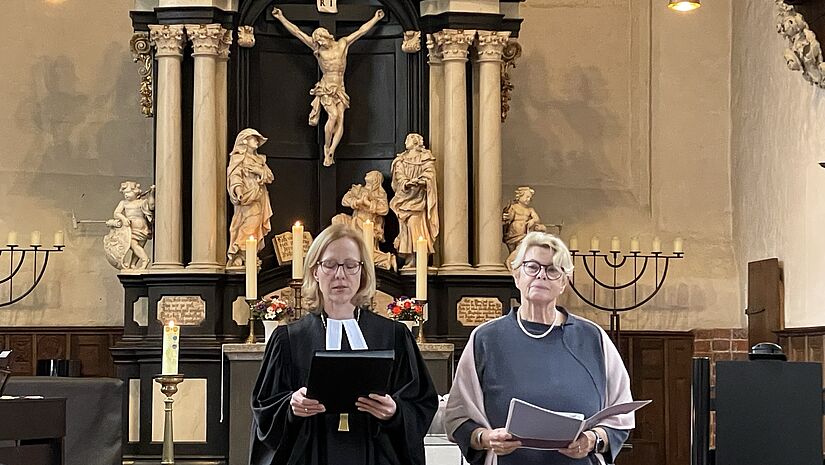 Bischöfin Steen und Synoden Präses Hillmann stehen bei den Fürbitten im Synoden-Gottesdienst vorne beim Altar.