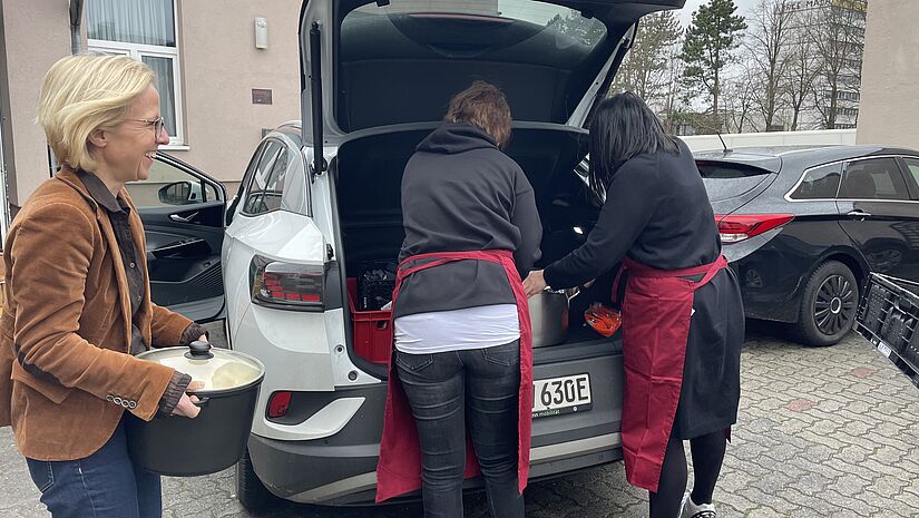 Drei Frauen verladen Töpfe in ein Auto