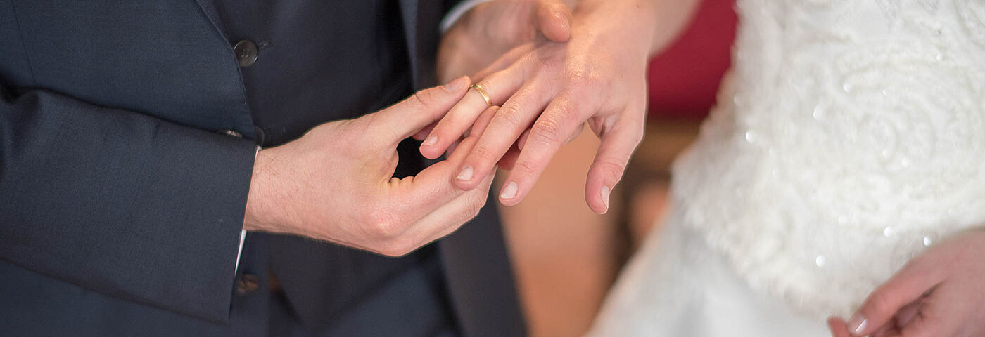 Ein Hochzeitspaar steckt sich die Ringe an