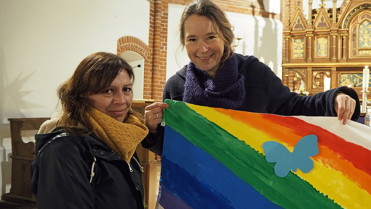 Mutter Daniela Wulff (l.) und Pastorin Mareike Hansen mit dem Regenbogen-Banner, auf dem die Schmetterlinge mit den Namen der verstorbenen Kinder angebracht werden.