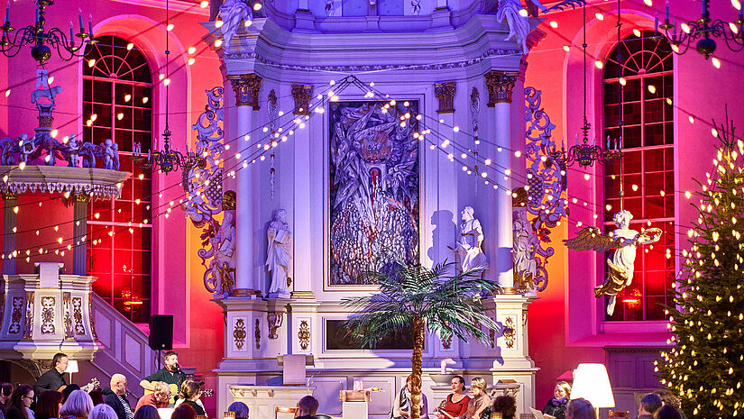 Eine mit Lichterketten und Scheinwerfen bunt erleuchtete Kirche. Eine Plastikpalme steht vor dem Altar. 