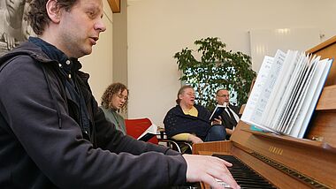 Das Foto zeigt Jan Simowitsch am Klavier beim Begleiten eines der neuen Lieder. Im Hintergrund rechts Propst Matthias Krüger, neben ihm sitzt Pastorin Kerstin Hansen Neupert.