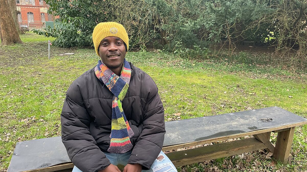 FOEJ Justice aus Ghana in seiner Einsatzstelle in Kiel auf einer Bank Im Rahmen seines Freiwilligen Ökologischen Jahres in Kiel hat Justice aus Ghana sein Engagement für den Umweltschutz entdeckt. Mittlerweile macht er eine Ausbildung in Deutschland.
